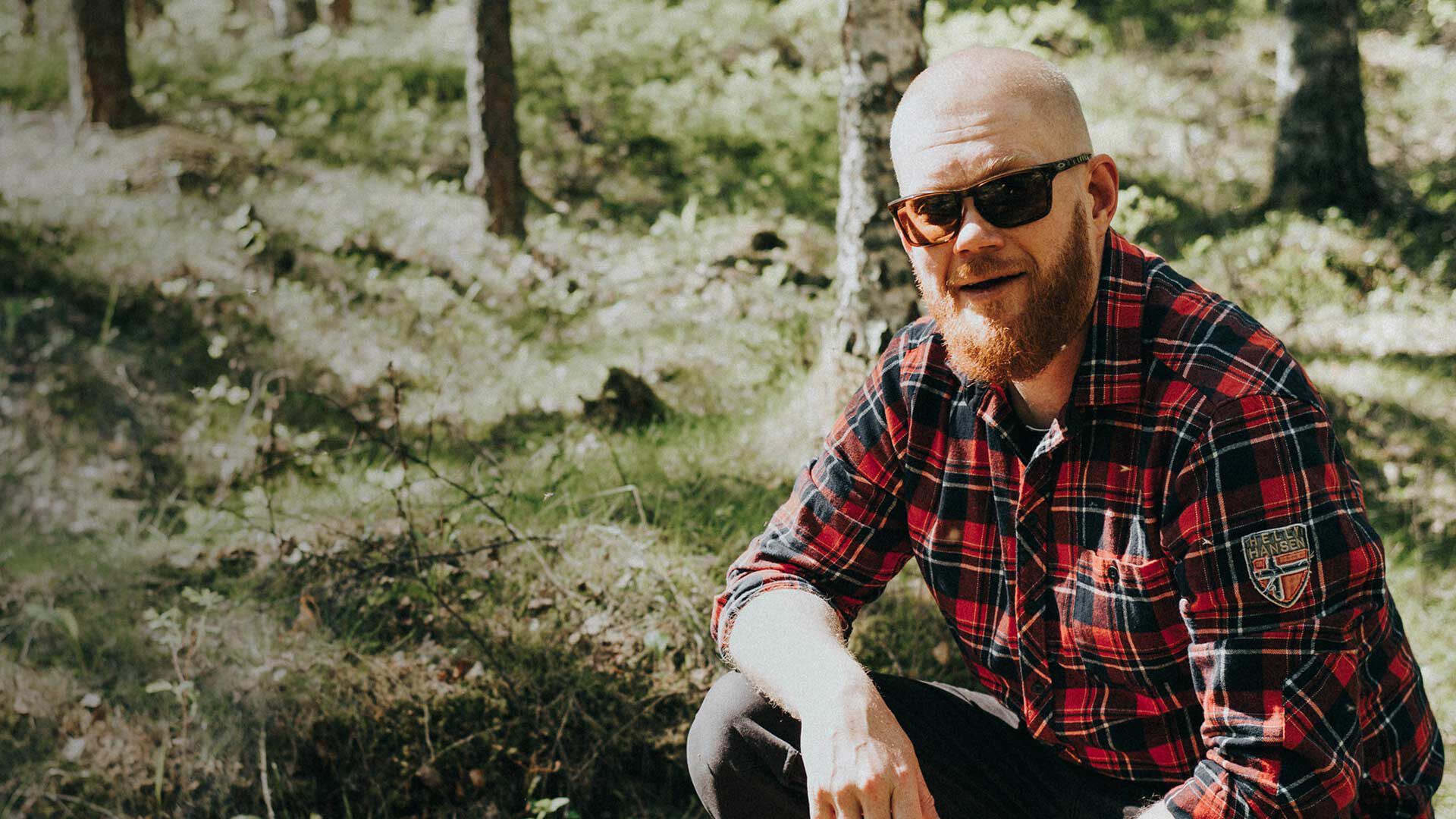Mies istuu mets&auml;ss&auml;, urheilulasit kasvoilla